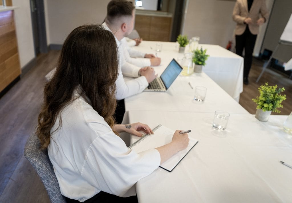 Attendees in white shirts writing notes during a business event in function room in Telford, ideal for conferences, meetings, and training sessions
