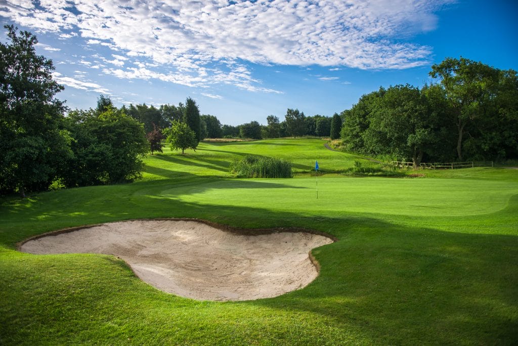 Golf green with large sand bunker on the 18 hole golf course in Telford at The Shropshire Golf Club, offering a challenging approach shot