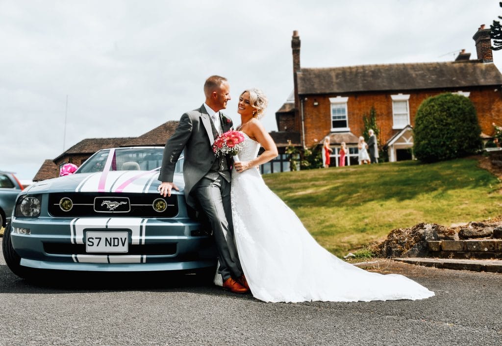 Just married couple posing in front of classic Mustang at wedding venue in Shropshire, celebrating their wedding day at The Shropshire