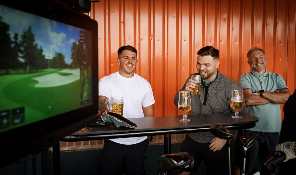 Group of friends enjoying beers together at the driving range bar at The Shropshire Golf Club in Telford, combining golf practice with socialising