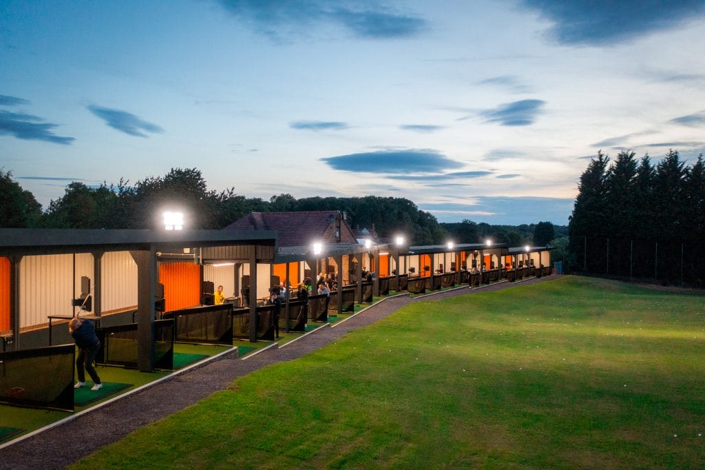 Exterior view of The Shropshire Golf Club’s TrackMan driving range in Telford at night, illuminated for evening golf practice and events