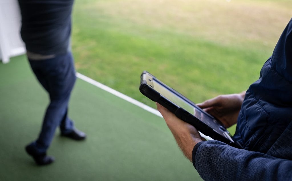 Golf coach using an iPad to track shots and analyse data during a golf lesson at The Shropshire Golf Club in Telford, incorporating advanced technology in golf coaching