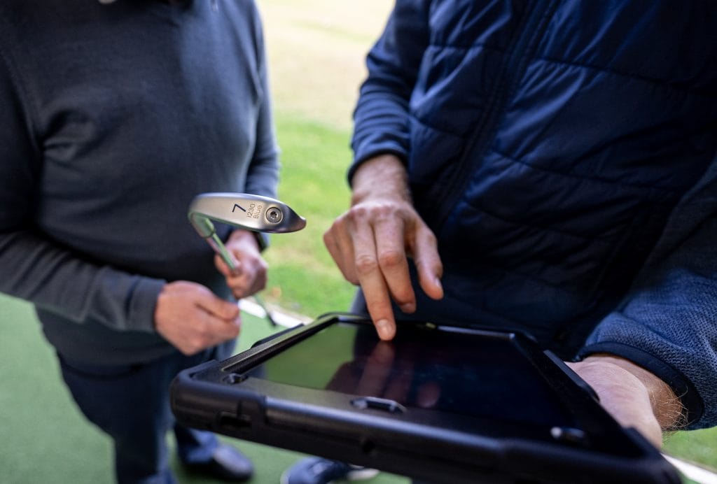 Golf coach reviewing performance stats with a player during a lesson at The Shropshire Golf Club in Telford, using data analysis to improve golf skills