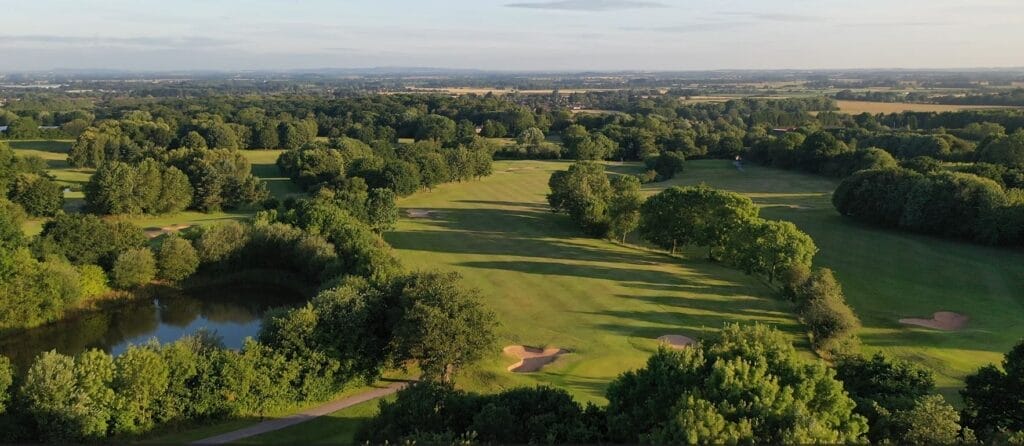 Aerial shot of multiple golf holes on the 18 hole golf course in Telford at The Shropshire Golf Club, showcasing course layout and natural scenery